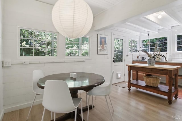 dining space featuring light wood finished floors, beam ceiling, and a wealth of natural light