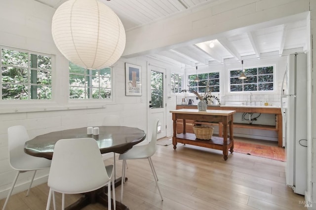 dining space with beam ceiling and light wood-style flooring