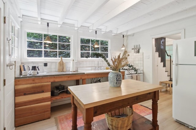 dining room featuring a wealth of natural light, beam ceiling, stairway, and light wood finished floors