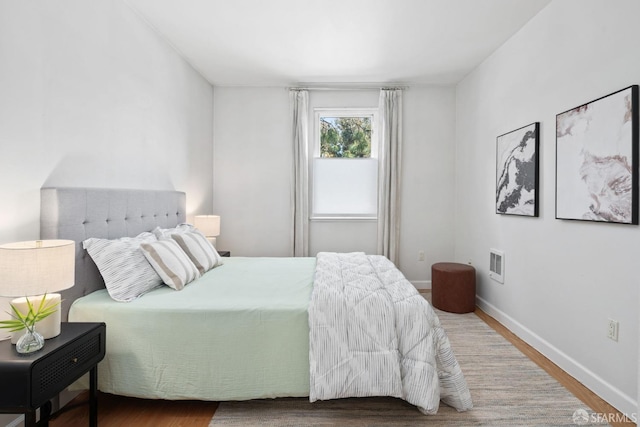 bedroom featuring baseboards, visible vents, and wood finished floors