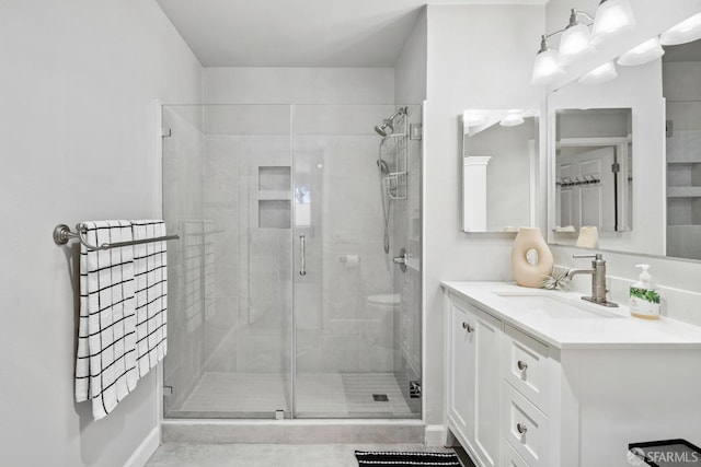 full bath with vanity, baseboards, and a stall shower
