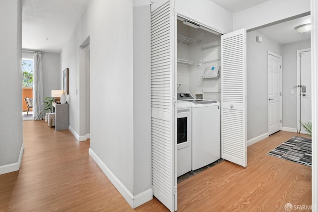 laundry room featuring baseboards, laundry area, light wood finished floors, and washer and clothes dryer