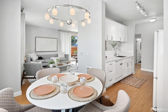 dining space featuring rail lighting, baseboards, and light wood-style floors