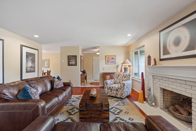 living area featuring recessed lighting, baseboards, a brick fireplace, and wood finished floors