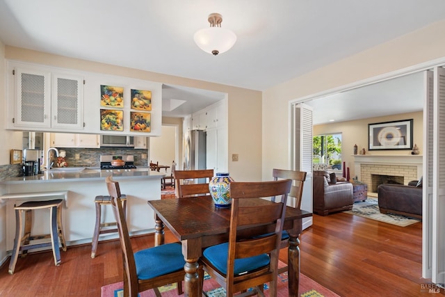 dining space with wood finished floors and a fireplace