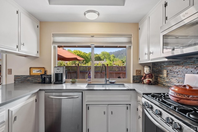 kitchen with light countertops, white cabinets, tasteful backsplash, a sink, and appliances with stainless steel finishes