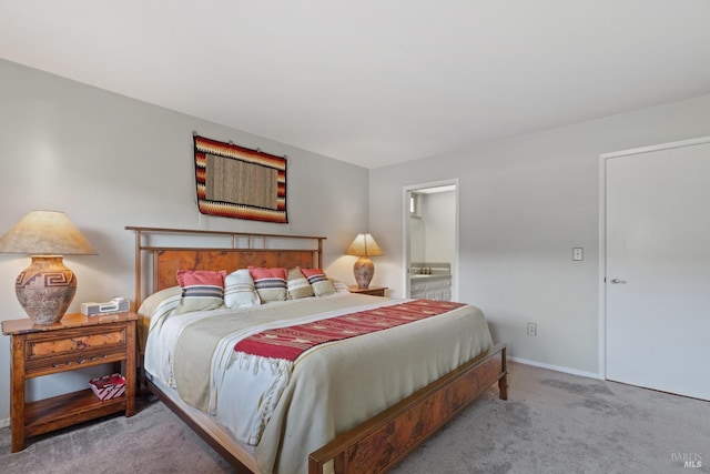 carpeted bedroom featuring baseboards and connected bathroom