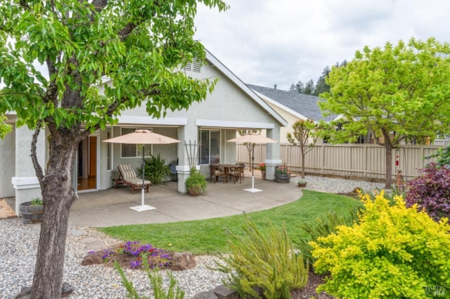 rear view of house featuring a patio, stucco siding, and fence