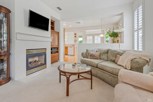 living room with recessed lighting, a tiled fireplace, visible vents, and light carpet