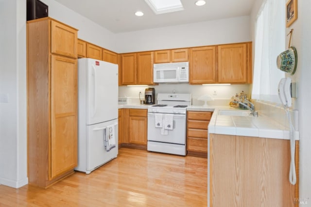 kitchen featuring a sink, white appliances, recessed lighting, tile counters, and light wood-style floors
