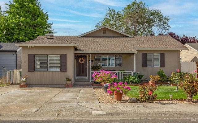 ranch-style home featuring covered porch, fence, a shingled roof, and stucco siding