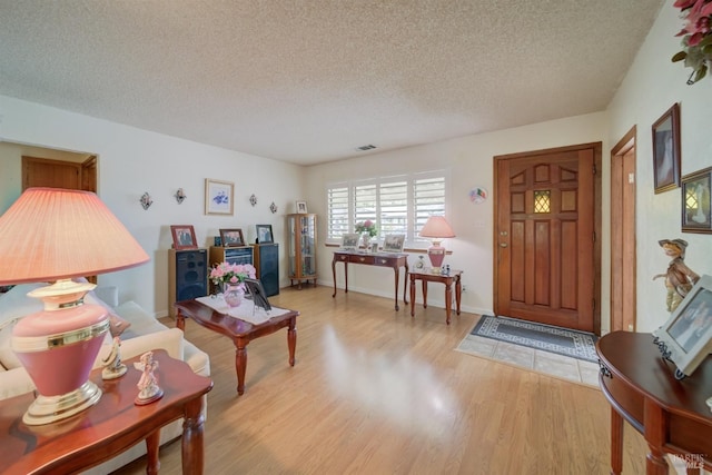 living area with light wood-style floors, visible vents, and a textured ceiling