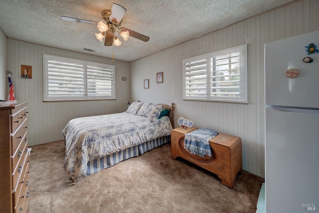 bedroom featuring freestanding refrigerator, multiple windows, visible vents, and carpet floors