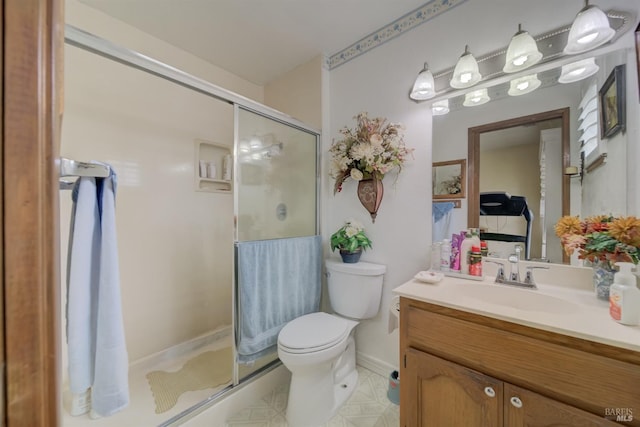 bathroom with vanity, toilet, baseboards, and a stall shower
