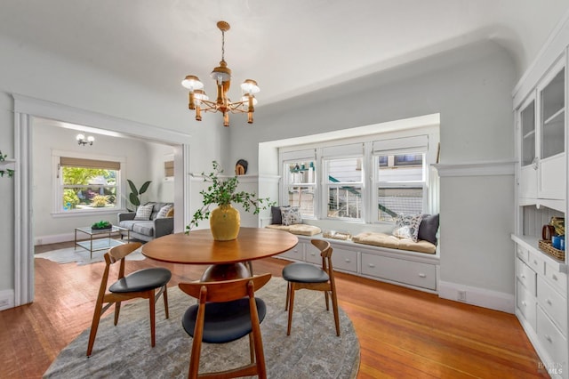 dining space with baseboards, an inviting chandelier, and light wood-style flooring