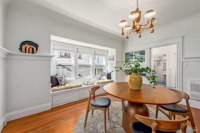 dining area with light wood finished floors, a chandelier, baseboards, and heating unit