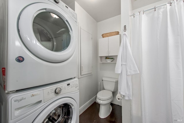 full bathroom with stacked washer / dryer, a shower with shower curtain, baseboards, and toilet
