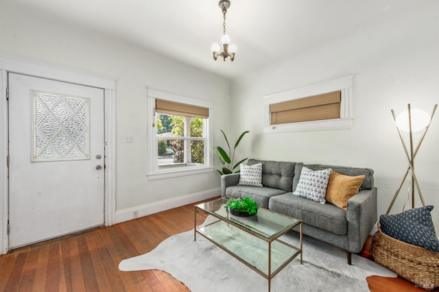 living area with baseboards, a chandelier, and wood-type flooring