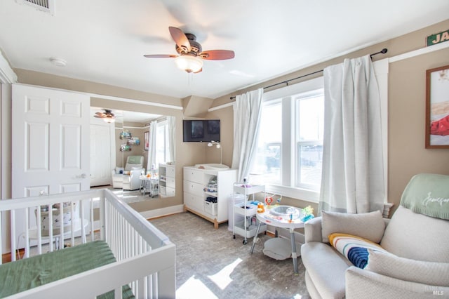 bedroom with a crib, multiple windows, visible vents, and ceiling fan