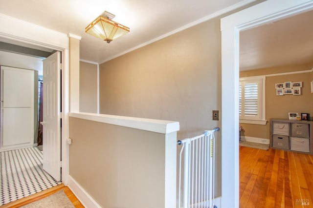 hallway featuring ornamental molding, baseboards, an upstairs landing, and wood finished floors
