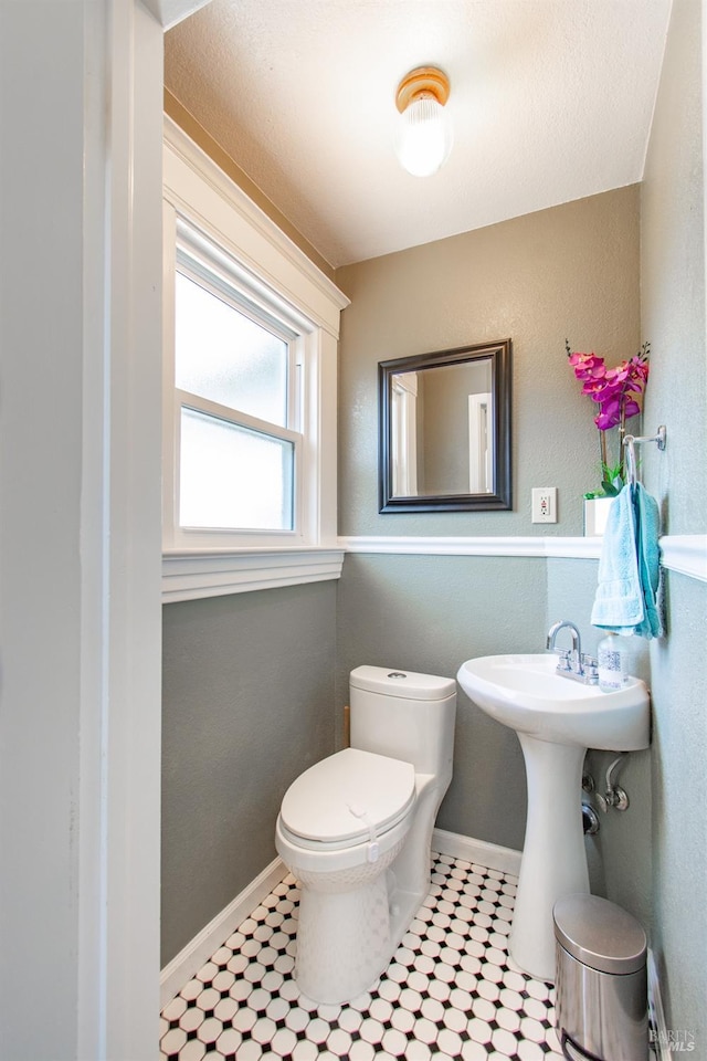 half bath featuring toilet, baseboards, and tile patterned floors