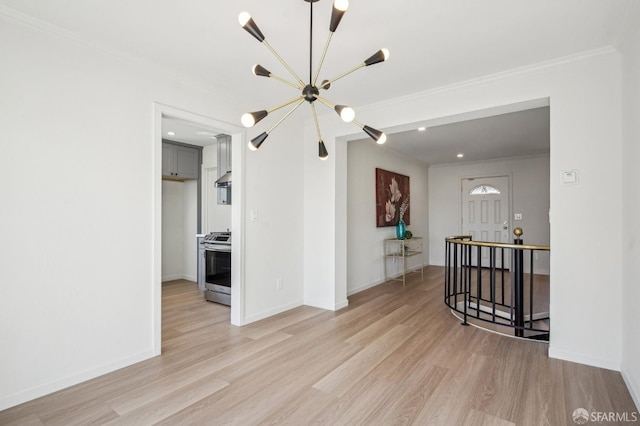 spare room with a chandelier, light wood-style flooring, ornamental molding, and baseboards