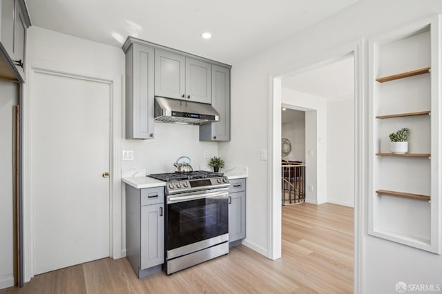kitchen featuring gas stove, gray cabinets, under cabinet range hood, light wood-style floors, and recessed lighting