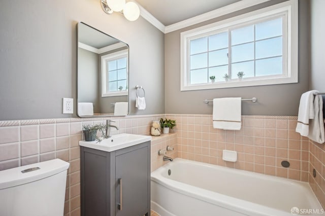 full bath with tile walls, toilet, vanity, a garden tub, and crown molding
