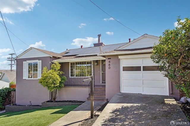 ranch-style home featuring an attached garage, concrete driveway, stucco siding, solar panels, and a front yard