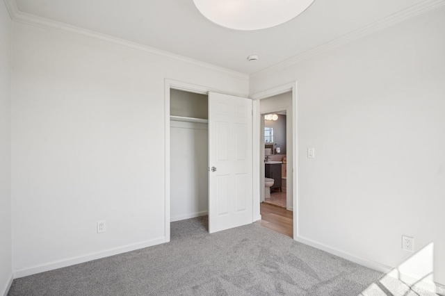 unfurnished bedroom with carpet floors, crown molding, baseboards, and a closet