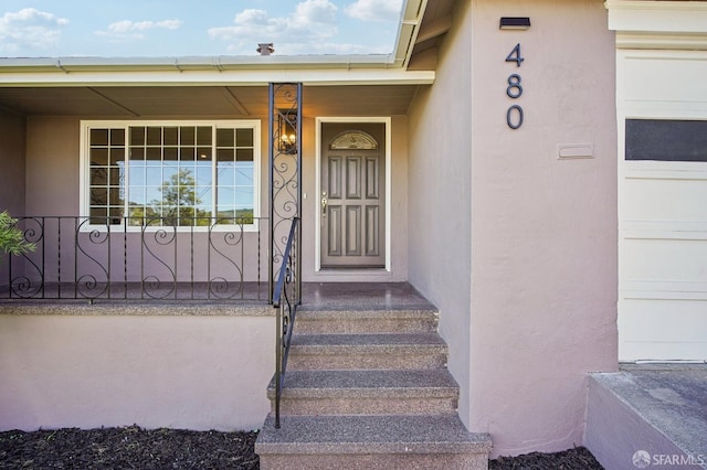 doorway to property with stucco siding and a porch