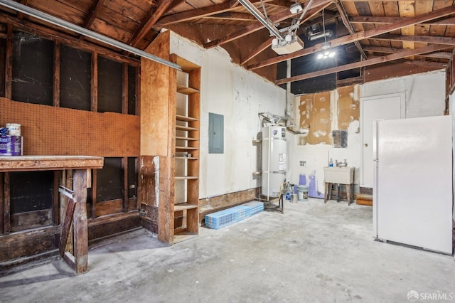 garage featuring freestanding refrigerator, secured water heater, electric panel, and a sink