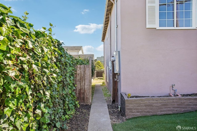view of side of home featuring stucco siding and fence