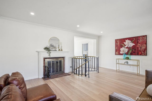 living room featuring wood finished floors, ornamental molding, recessed lighting, baseboards, and a fireplace