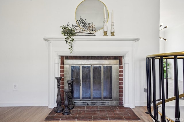 detailed view of a fireplace, baseboards, and wood finished floors