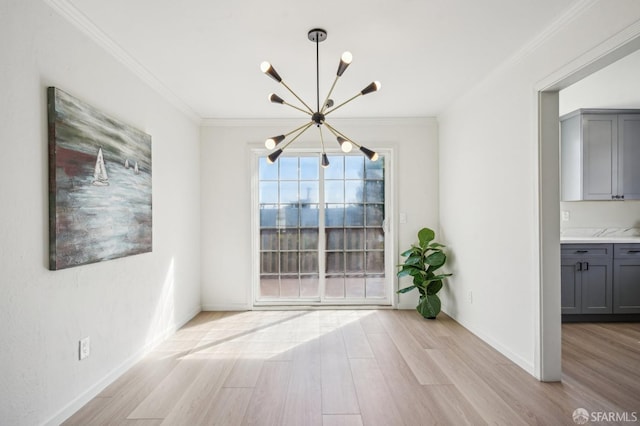 unfurnished dining area featuring a chandelier, light wood-style floors, crown molding, and baseboards