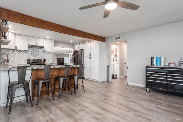 kitchen with under cabinet range hood, ceiling fan, visible vents, stainless steel electric stove, and a peninsula