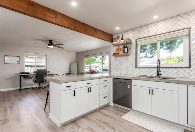 kitchen featuring a sink, a peninsula, tasteful backsplash, dishwasher, and white cabinetry