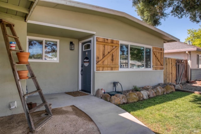 view of exterior entry featuring fence and stucco siding