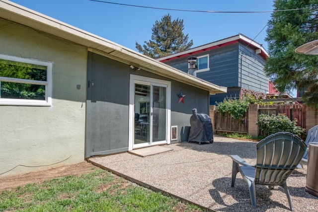 rear view of property featuring fence, stucco siding, and a patio area