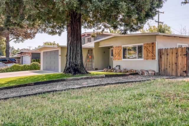 ranch-style home featuring stucco siding, driveway, fence, and a front yard