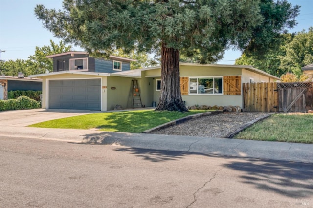 view of front of property with a gate, fence, concrete driveway, stucco siding, and a front yard