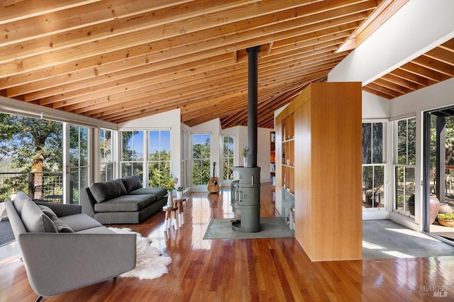 sunroom / solarium featuring a wood stove, plenty of natural light, and vaulted ceiling