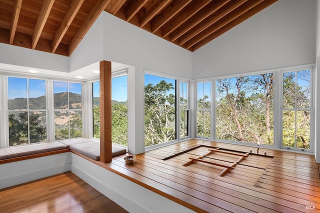 unfurnished sunroom featuring a mountain view, high vaulted ceiling, wood ceiling, and wood finished floors