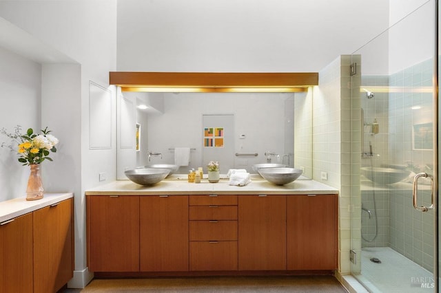 full bathroom with double vanity, a stall shower, and a sink