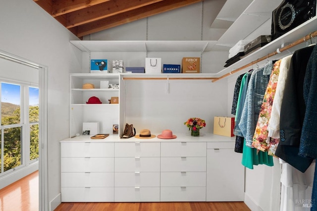 walk in closet with lofted ceiling with beams and light wood-style flooring