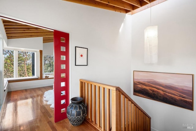 hall featuring an upstairs landing, baseboards, wood finished floors, and lofted ceiling