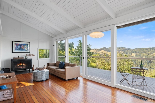 sunroom / solarium featuring beamed ceiling, a deck with mountain view, visible vents, and hardwood / wood-style flooring