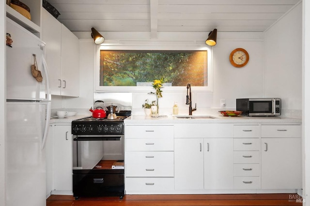 interior space featuring freestanding refrigerator, black gas range, a sink, stainless steel microwave, and light countertops