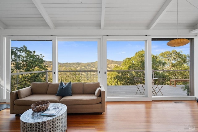sunroom with beamed ceiling, a mountain view, visible vents, and a wealth of natural light